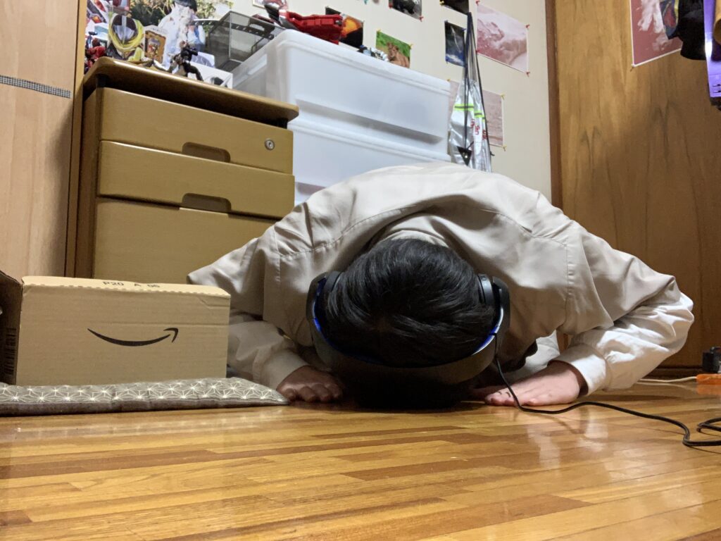 床に座ってヘッドフォンを装着し、前に伏せている人物の写真